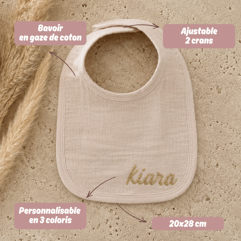 bavoir en gaze de coton beige posé sur une table en travertin. Cadeau de bébé