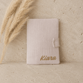 protège carnet de santé en gaze de coton beige, un prénom de bébé est écrit en doré.