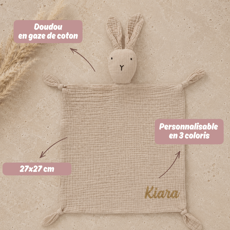 doudou en gaze de coton beige posé sur une table en travertin. Cadeau de bébé